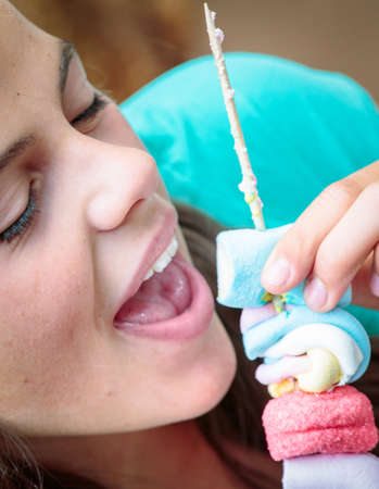 closeup of pretty young girl eating a delicious marshmallow skewerの写真素材