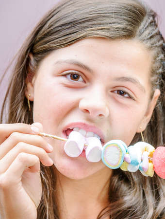 closeup of pretty young girl eating a delicious marshmallow skewerの写真素材