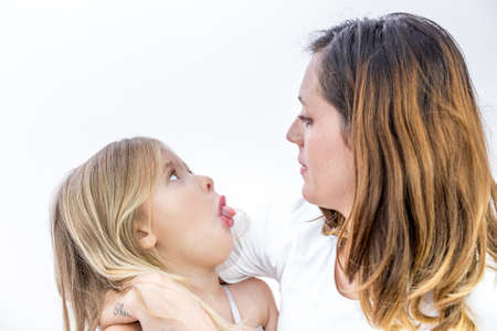 Closeup of a smiling young woman playing with her child on white backgroundの写真素材