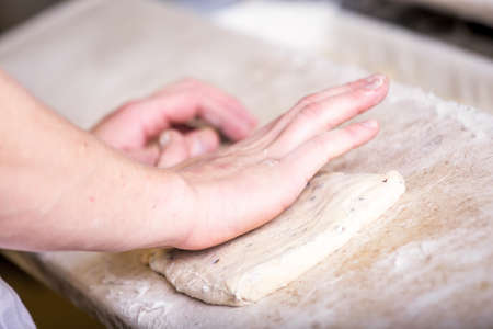 Close-up the hand of a baker kneading and shaping doughの写真素材