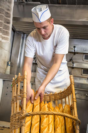 baker filing a delicious crusty baguettes in a basket