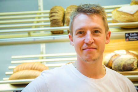 smiling man selling bread in a bakery