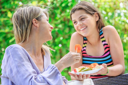 Mother and daughter eating fruits in outdoorの写真素材