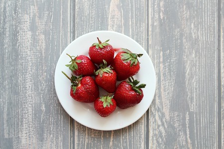 Strawberries in white plate on wooden grey desk. Stock photo.の写真素材