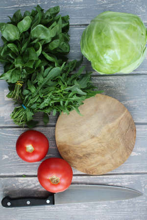 Composition of vegetables on grey wooden desk. Tomato, cucumber, cabbage, basil, arugula. Top view. Modern photography. The best for book with recipies.の写真素材