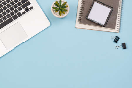 Workspace home office blue background with notebook, coffee, clips and accessories. Top view with copy space, flat lay.の写真素材