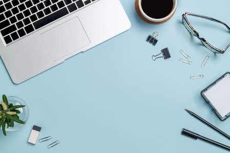 Top view workspace mockup on blue background with notebook, pen, coffee, clips and accessories.