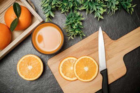 Fresh orange juice in glass dark stone background with kitchen utensils.の写真素材