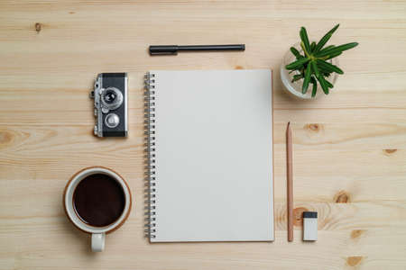 Top view workspace mockup on wood table with notebook, pen, coffee, clips and accessories.