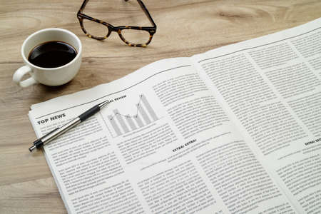 Newspaper on wooden desk with coffee and eyeglasses.の写真素材