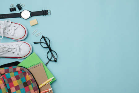 Top view school supplies on blue background with copy space.