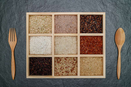 Brown rice, Black Jasmine rice, Red jasmine rice and Riceberry in boxes lon black desk.の写真素材