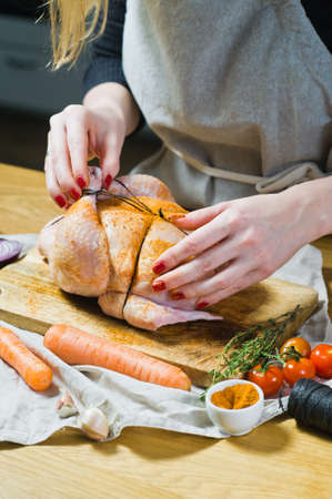 The hands of the chef rubbed the raw chicken with spices. Dark background, side viewの写真素材