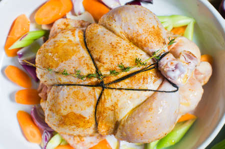 A baking sheet with a piece of raw chicken in the spices. wooden background, top view