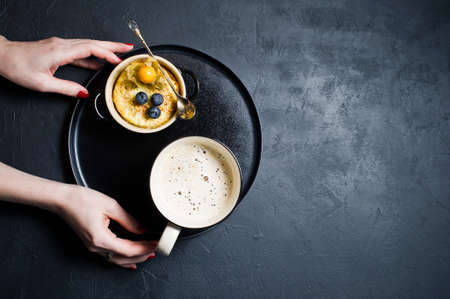 Concept healthy Breakfast, rice pudding and a Cup of coffee. Dark background, top view, hands, space for textの写真素材
