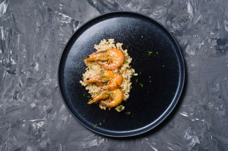Italian risotto with shrimp on a black plate.. Dark background, top view, space for textの写真素材