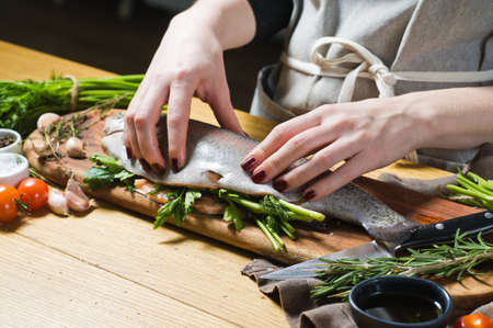 The chef stuffed raw trout with parsley and dill. Ingredients rosemary, lemon, tomatoes, garlic,...