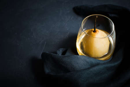 Pear poached in a glass. Black background, top view