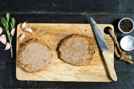 Roast Beef steak, cooking. Top view, black background, space for text.