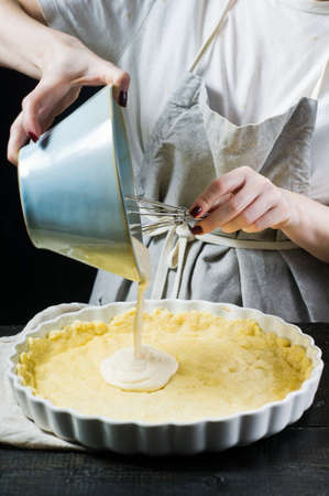 The chef prepares a cake in a baking dish. Side view, black background, close up