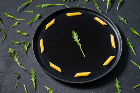 The concept of pasta Penne with arugula, minimalism. Dark background, side viewの写真素材