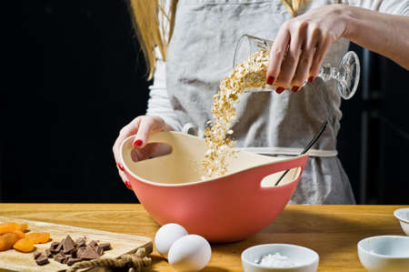 The chef prepares oatmeal cookies, pours oatmeal into a bowl. Ingredients oat flakes, butter, sugar,...