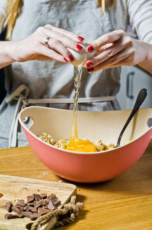 The chef is preparing cookies, breaks the eggs into a bowl. Ingredients: oat flakes, butter, sugar,...
