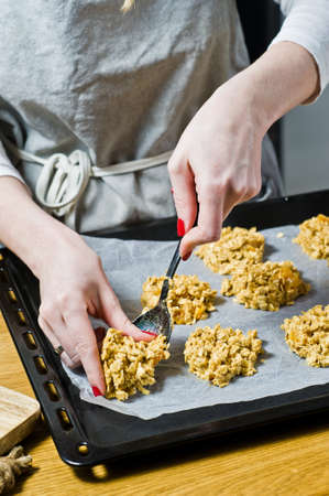 The chef is preparing cookies, spread the dough on the trays. Side view, black background, kitchen.の写真素材
