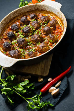 Italian meatballs in tomato sauce in a baking dish. Black background, top viewの写真素材