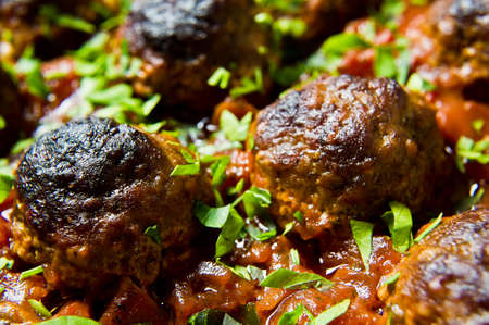 Swedish meatballs in tomato sauce in a baking dish. Black background, top view, close up