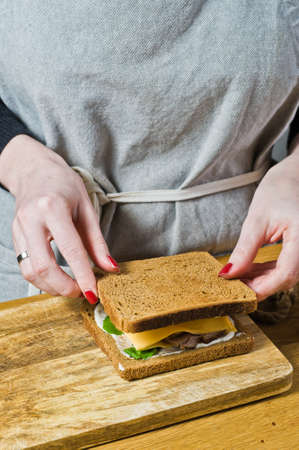 The chef prepares a sandwich with toast of black bread. Black background, side view, kitchenの写真素材