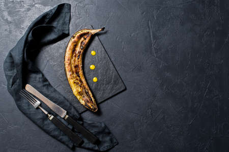 Baked bananas with honey on a black stone Board. Black background, top view, close upの写真素材