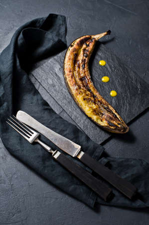 Fried banana with honey on a black stone Board. Black background, top view, close upの写真素材
