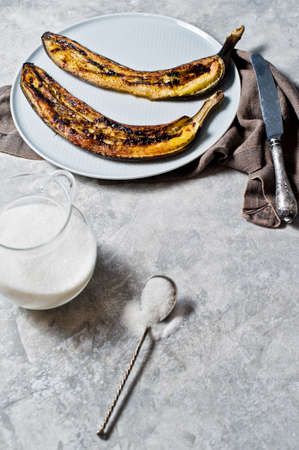 Baked bananas with honey on a grey plate. Gray background, side view, space for textの写真素材
