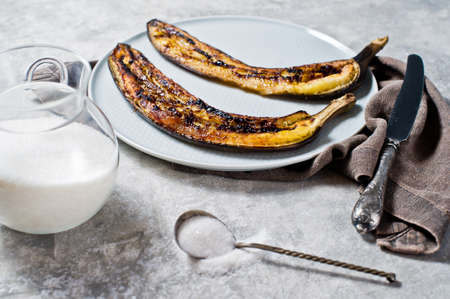 Fried bananas with honey on a grey plate. Gray background, side viewの写真素材