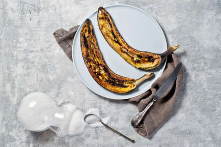 Baked bananas with honey on a grey plate. Gray background, top view, space for textの写真素材