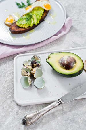 Sandwich with avocado and egg on toast of black bread. Grey background, side viewの写真素材