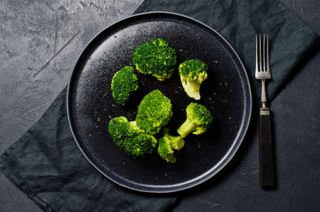 Boiled broccoli on a black plate. Black background, top viewの写真素材