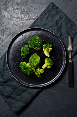Boiled broccoli on a black plate. Black background, top viewの写真素材