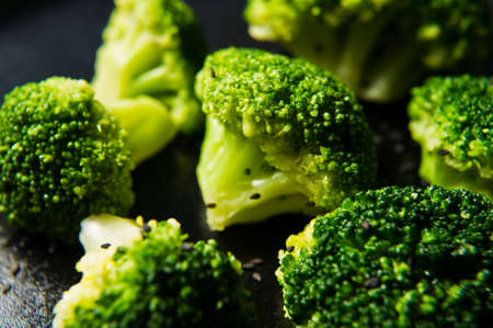 Boiled broccoli on a black plate. Black background, side view, close-upの写真素材