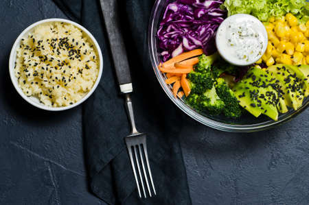 Salad bowl, healthy and balanced food. Ingredients broccoli, corn, carrots, couscous, lettuce, cabbage, sauce. Black background, top view, space for textの写真素材