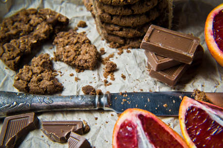 A stack of homemade chocolate chip cookies with orange, orange slices and chocolate. Black...
