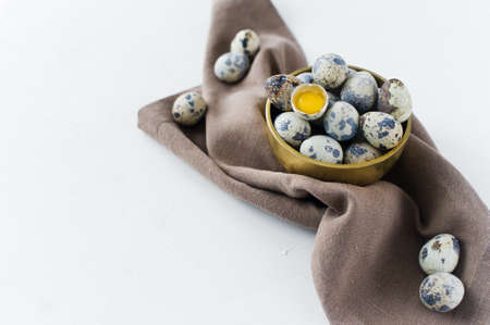 Quail eggs in a Golden bowl, one broken egg. White background, side55 view, space for text