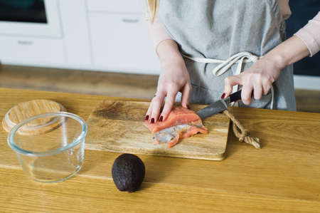 The chef cuts Atlantic salmon for a sandwich with avacado and egg. Side view, the background of the...