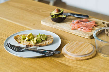 Toast with avocado on a plate, wooden table. Side view, the background of the kitchen