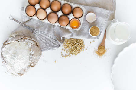 Ingredients for homemade baking. Eggs, milk, flour, sugar. White background, top view, space for textの写真素材
