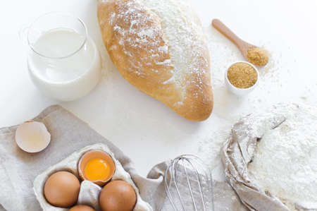 Ingredients for baking homemade bread. Eggs, milk, flour. White background, side view
