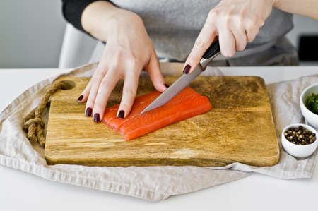 The chef cuts salmon fillets on a wooden chopping Board. White background, top view, space for textの写真素材