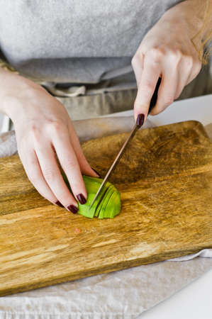 The chef peels avocado on a wooden chopping Board. White background, top view