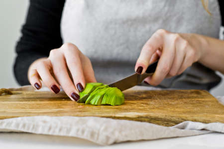 The chef peels avocado on a wooden chopping Board. White background, side view